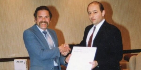 John Greenwood and Ralph Strozza shake hands in a formal setting, marking a significant moment in Interpro’s early history.